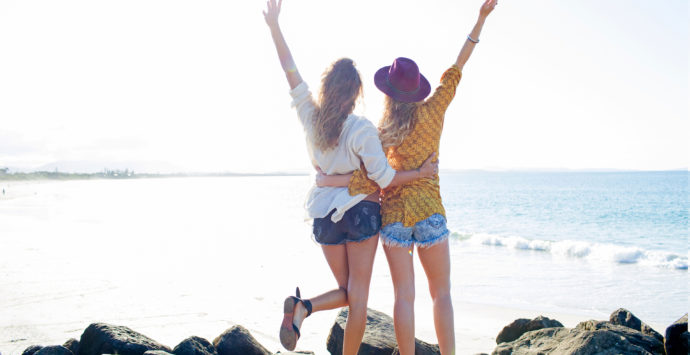 Two females arms raised on the beach