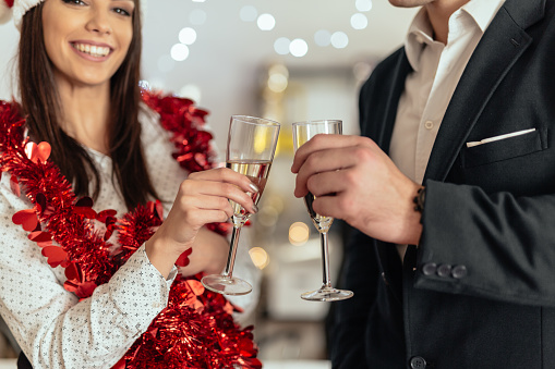Young couple drinking champagne and celebrating christmas in the office