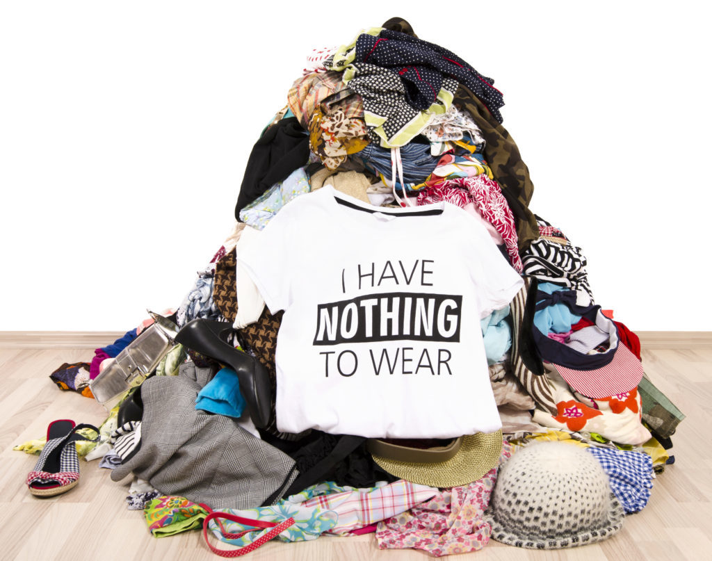 Big pile of clothes thrown on the ground with a t-shirt saying nothing to wear. Close up on a untidy cluttered wardrobe with colorful clothes and accessories,